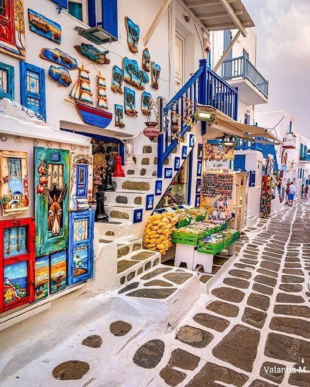 Colorful Greek street with blue balconies, white buildings, and stone-paved walkway
