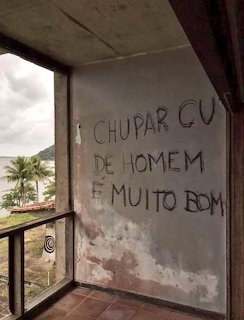 Worn balcony wall covered in graffiti with a window view of a tropical beach and palm trees