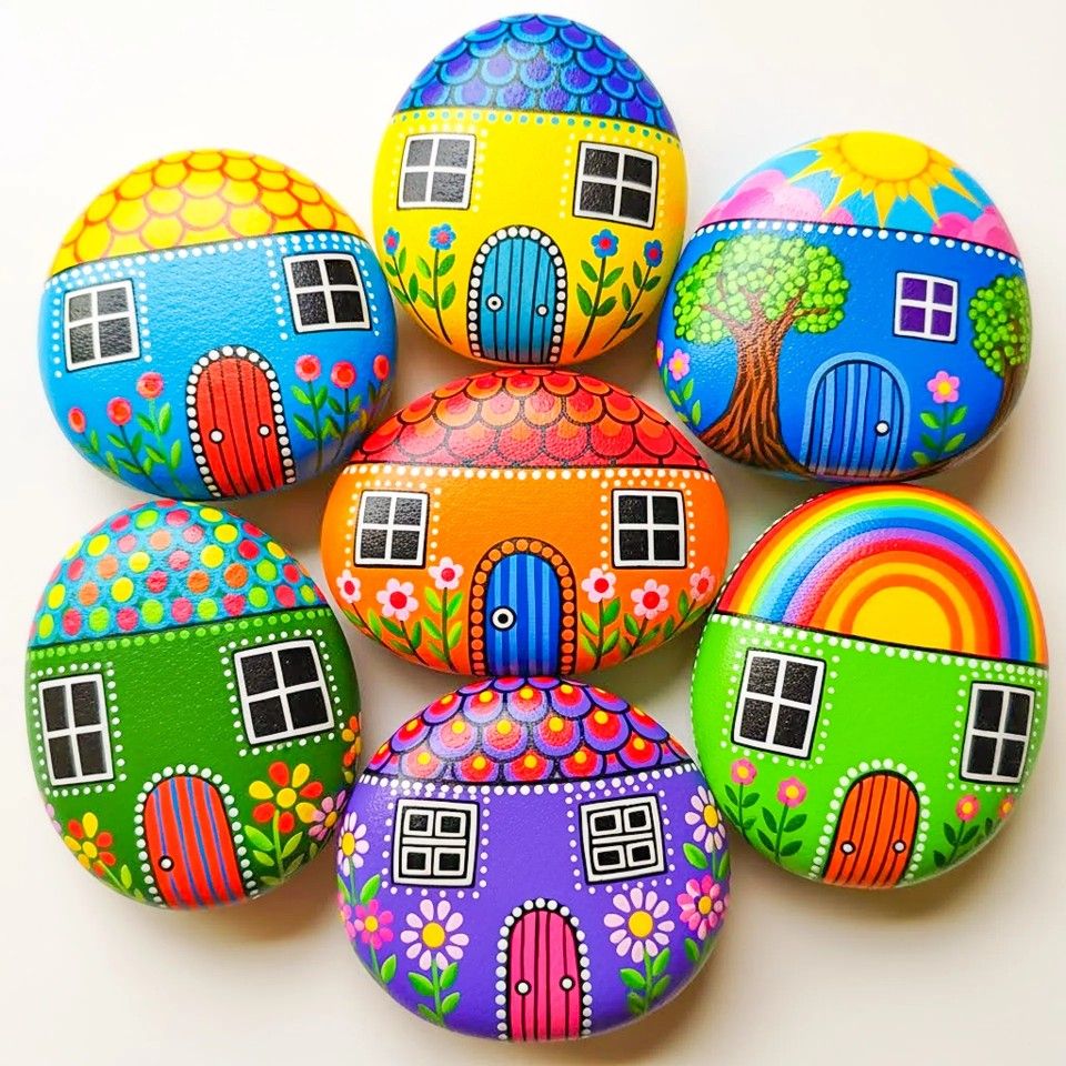 Nine decorative stones painted as colorful tiny houses with doors, windows, and floral patterns