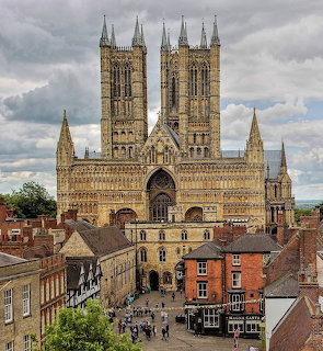 Lincoln Cathedral towering above historic street buildings under a cloudy sky