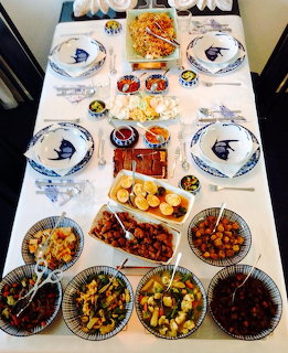 Overhead view of Indonesian rijsttafel with many colorful dishes and plates arranged on white table