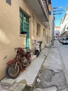 Two parked motorcycles beside a beige building in a narrow urban alley