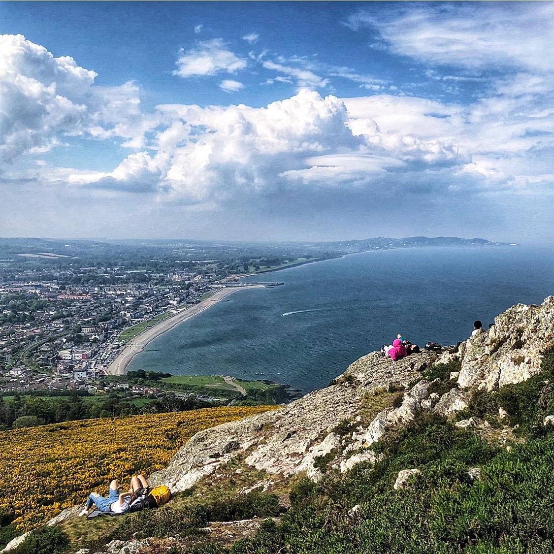 View from Bray Head over the coastline, sea, town, and rocky hillside under a cloudy sky