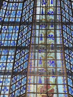 View upward at a geometric stained glass ceiling with blue and gold decorative panels