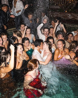 Bride and groom celebrating with guests at an outdoor wedding pool party
