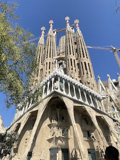 Low-angle view of Sagrada Família cathedral spires and ornate stone facade in Barcelona under a blue sky
