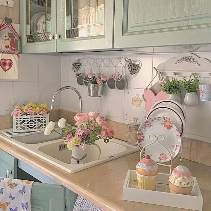 Shabby chic kitchen with mint cabinets, pink roses in sink, floral plates, and cupcake decorations