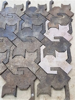 Interlocking cat-shaped concrete paving tiles in gray and brown tones arranged in a tessellating pattern