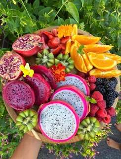 Colorful tropical fruit platter with dragon fruit, oranges, beries, and kiwi on a wooden board