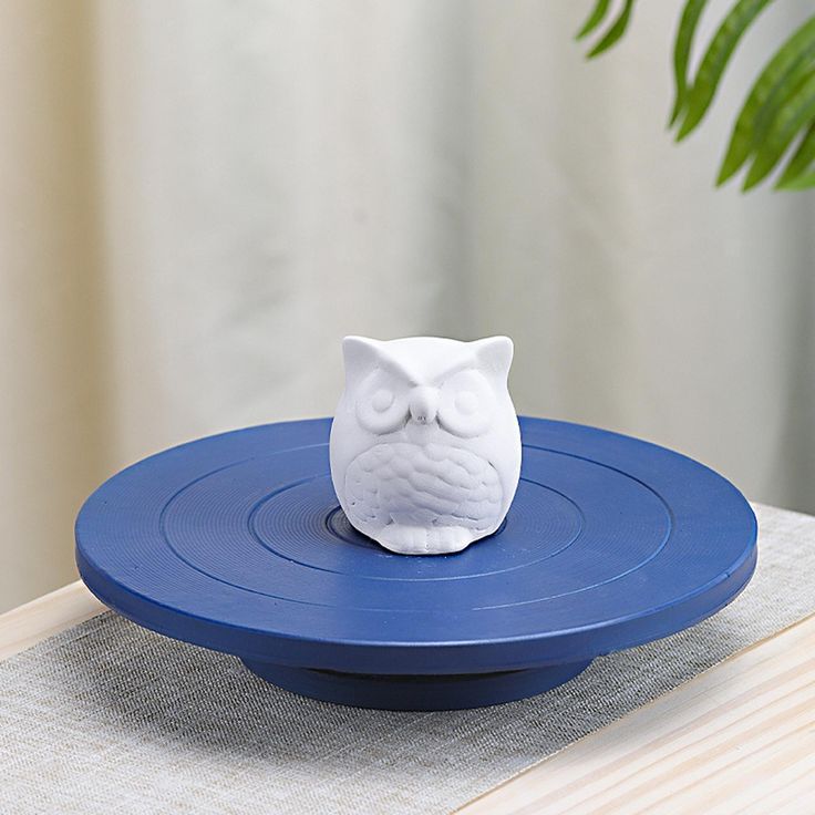 White owl figurine on a blue round turntable indoors