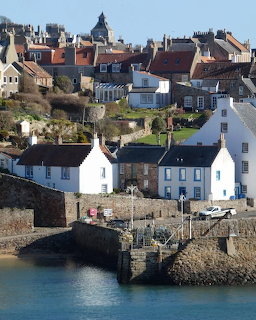 Scottish coastal village of Crail with white houses along a harbour and hillside buildings behind