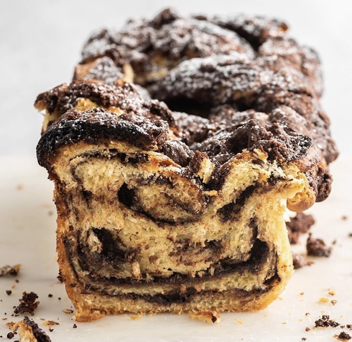 Close-up of a chocolate babka slice with dark chocolate swirls and powdered sugar