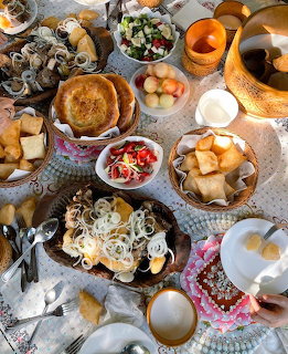 Overhead view of traditional Kazakh breakfast with baursak, sweets, fruits, and tea on decorative table setting