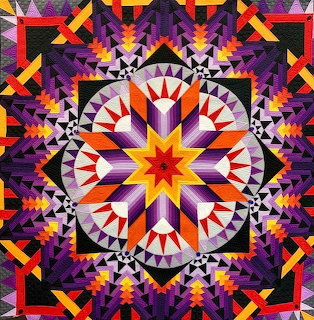 Colorful geometric quilt with central star medallion and symmetrical triangular pattern borders