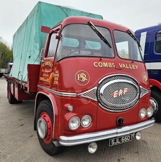 Red vintage ERF truck parked outdoors with a covered trailer load