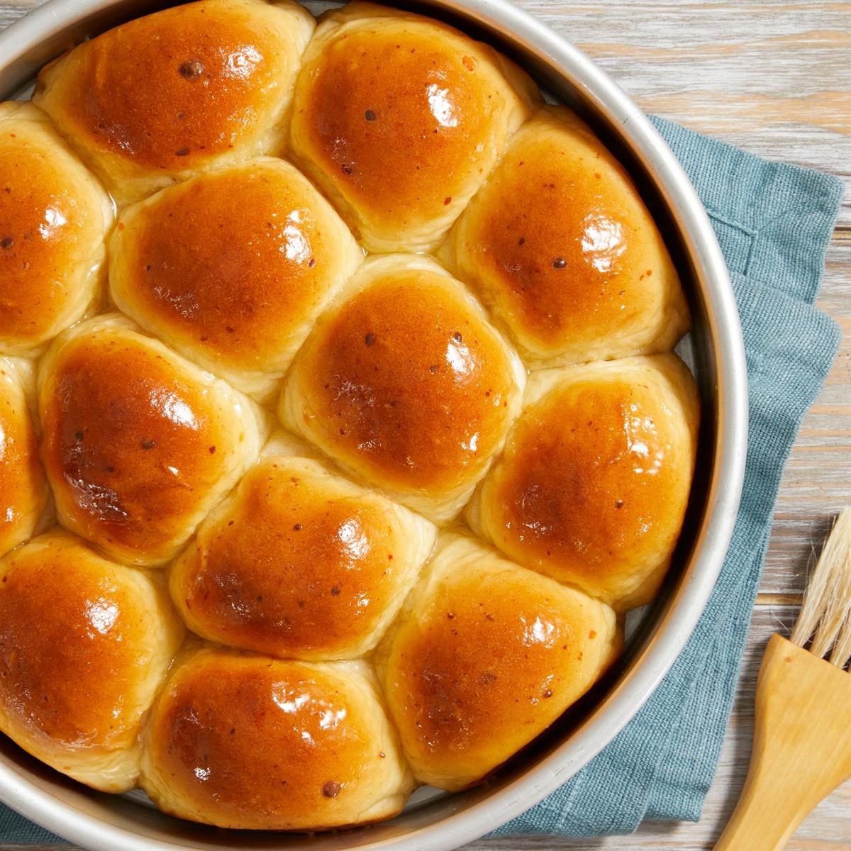 Golden dinner rolls in round pan on wooden table