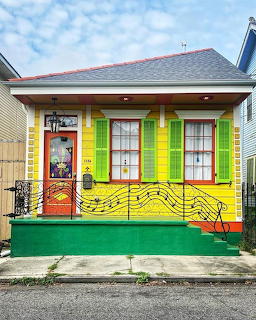 Yellow house with painted musical notes and treble clef mural on facade