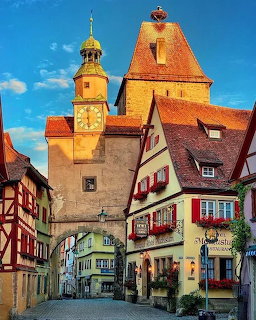 Medieval German street with clock tower, archway, and colorful half-timbered houses in Rothenburg ob der Tauber