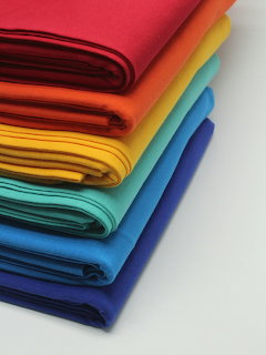 Stack of neatly folded rainbow colored fabrics arranged in spectrum order from red to purple