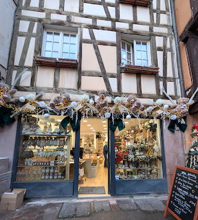 Half-timbered building storefront decorated with Christmas lights and festive garlands at dusk