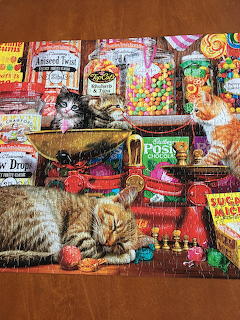 Two fluffy kittens lying among colorful candy jars and gumballs in a vintage sweet shop setting