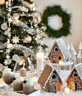 Gingerbread houses with candles beside a decorated Christmas tree in a cozy holiday setting