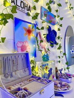 Beach-themed vanity with shells, floral wall art, ivy vines, and fairy lights indoors