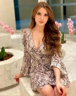 Young woman with long brown hair in a snakeskin print wrap dress sitting outdoors