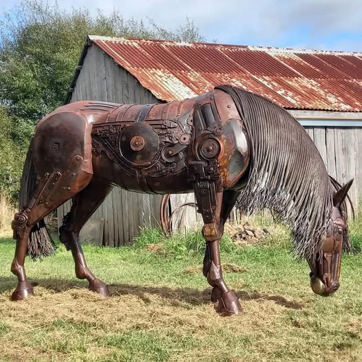 Rusted metal horse sculpture made from industrial scrap parts in front of old barn
