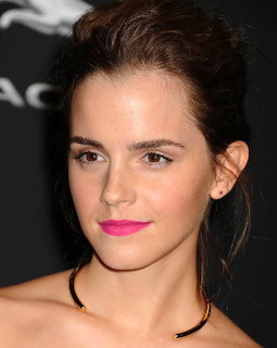 Close-up portrait of Emma Watson with pink lipstick and dark hair against a black background