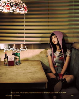 Young woman in pink hoodie sitting on a dark couch in a mody retro room with a stained glass lamp