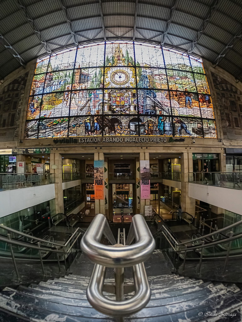 Interior view of Abando train station in Bilbao with decorative stained glass ceiling and central art installation