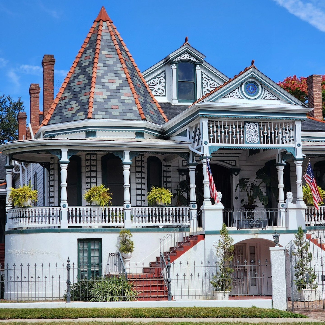 Victorian house with conical slate tower, wraparound porch, ornate trim and multiple gables