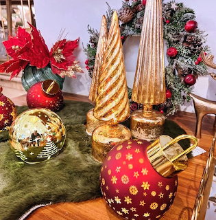 Gold and red Christmas ornaments with decorative trees and poinsettias on table