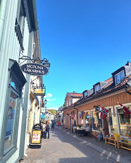 Colorful wooden shop buildings along a pedestrian street in Sigtuna, Sweden with signs and blue sky