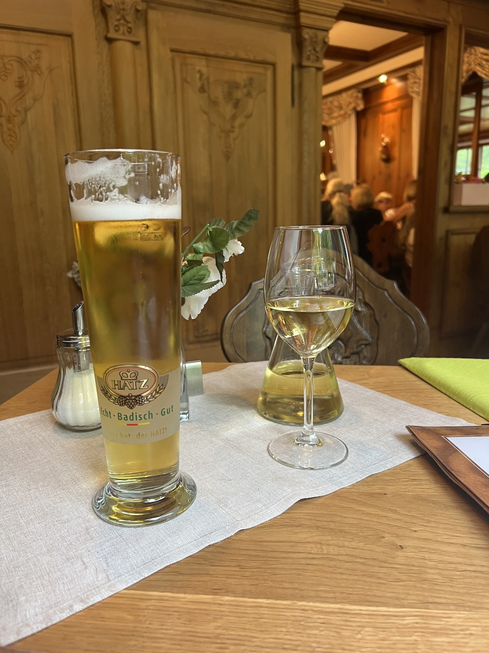 Tall beer glass and wine glass on table in rustic restaurant interior