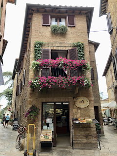 Brick shop building with flower-filled balconies on a narrow wet street