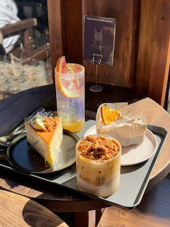Tray with cheesecake, sandwich, iced coffee and citrus drink on a cafe table