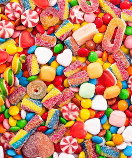Colorful assortment of candies including gummies, lollipops, and jelly beans on blue background