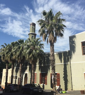 Auwal Mosque in Cape Town with a minaret, palm trees, and a pale exterior under a blue sky