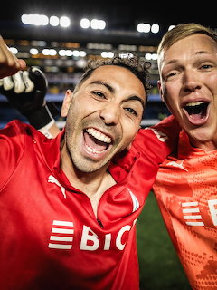 Two soccer players celebrating excitedly on the field at night in a packed stadium