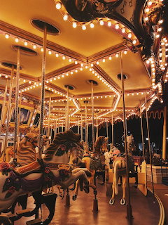 Illuminated carousel with carved horses and golden lights at night