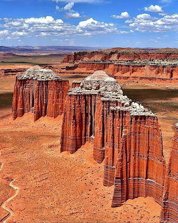 Tall red sandstone rock formations and pillars in anrid Southwest desert landscape under blue sky