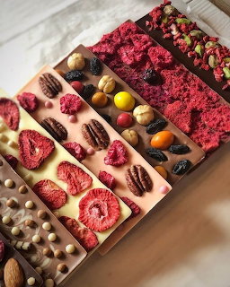 Assorted artisan chocolate bars decorated with dried fruits, nuts, and beries arranged in rows
