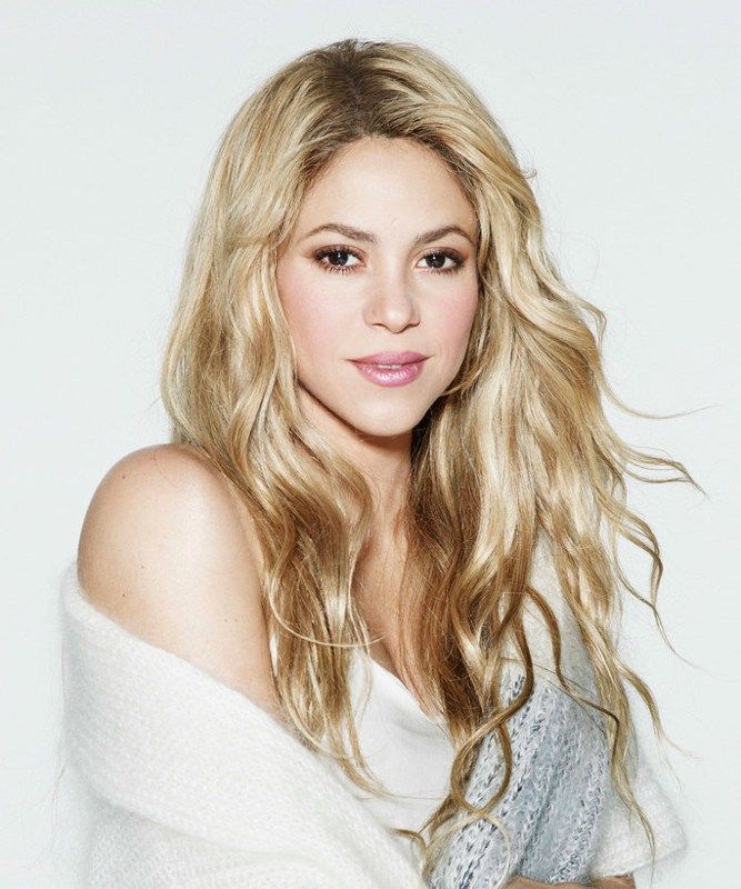 Young blonde woman with long wavy hair wearing a white off-shoulder top, portrait photo