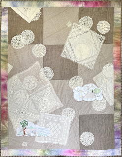Patchwork quilt artwork with white lace doilies and appliqué details on a muted fabric background