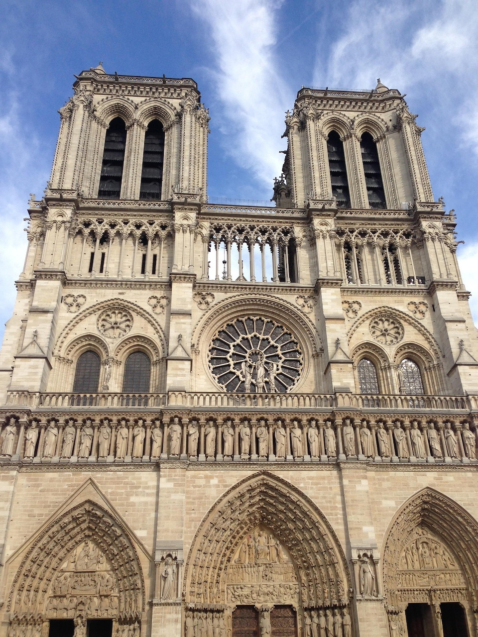 Front facade of Notre-Dame Cathedral in Paris with twin towers and Gothic architecture against blue sky
