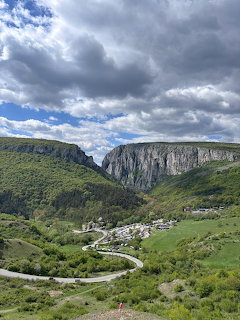 Cheile Turzii gorge with limestone cliffs, green valley, winding road, and dramatic cloudy sky