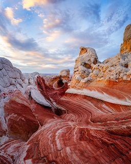 Swirling red and white sandstone formations at White Pocket under cloudy sky