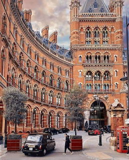 Gothic red brick St Pancras hotel building in London with black taxi and red phone booth on street